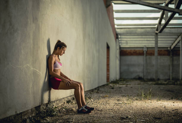 istock Young athletic woman doing wall sit on a sports training. 1030299962
