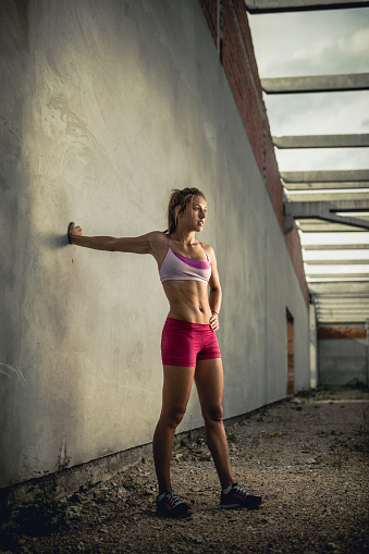 Young athletic woman doing stretching exercises before sports training in an old ruin.