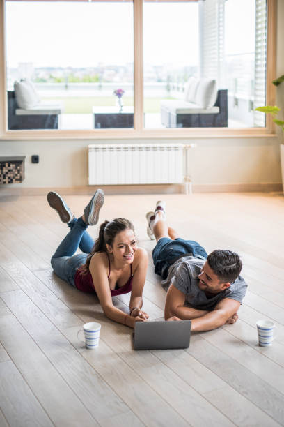 istock Cheerful couple having fun while using laptop on the floor at new apartment. 1030308110