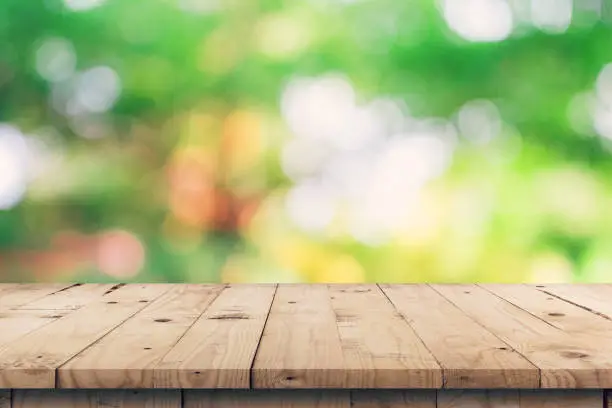 Photo of Empty wooden table top and green bokeh display montage for product with space.