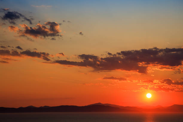 Beautiful bright sun going down over mountains and sea