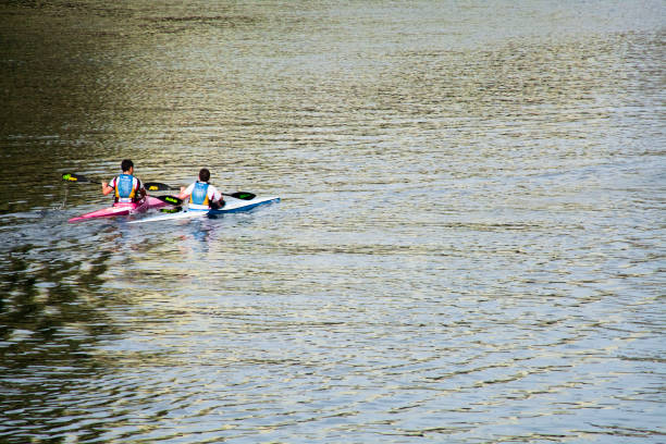 Pontecesures, Spain- 9 May, 2018: Rear view of two young males canoeing , sitting down, rowing. Tranquil idyllic scene at dusk suitable for backgrounds and copy space available. Pontevedra province, Galicia, Spain.