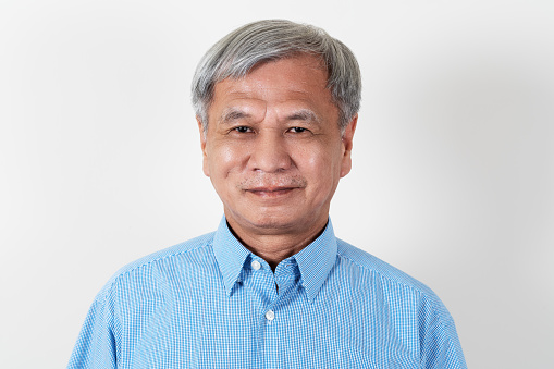 Portrait of attractive senior asian man smiling and looking at camera in studio with white isolated background feeling positive grandpa. Headshot of mature older chinese man or father concept.