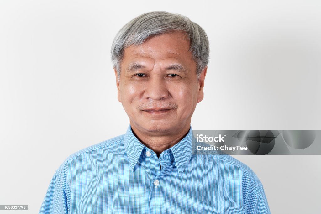 Portrait of attractive senior asian man smiling and looking at camera in studio with white isolated background feeling positive grandpa. Headshot of mature older chinese man or father concept. Portrait Stock Photo