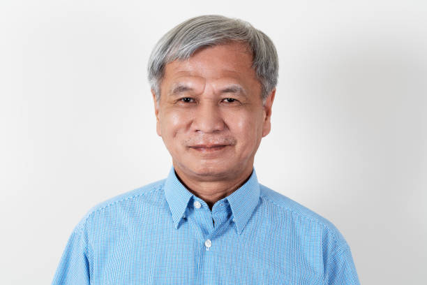 Portrait of attractive senior asian man smiling and looking at camera in studio with white isolated background feeling positive grandpa. Headshot of mature older chinese man or father concept. Portrait of attractive senior asian man smiling and looking at camera in studio with white isolated background feeling positive grandpa. Headshot of mature older chinese man or father concept. men old senior adult human face stock pictures, royalty-free photos & images