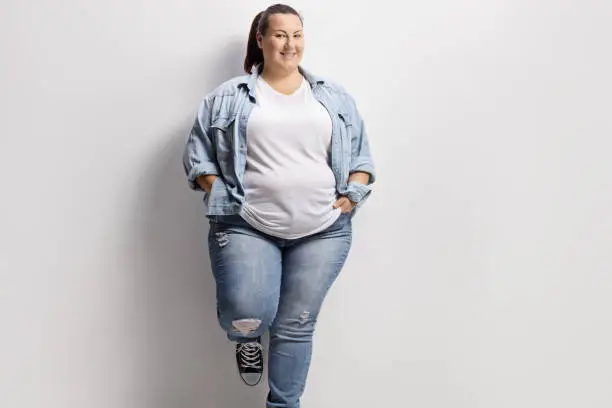 Photo of Young overweight woman standing against a wall