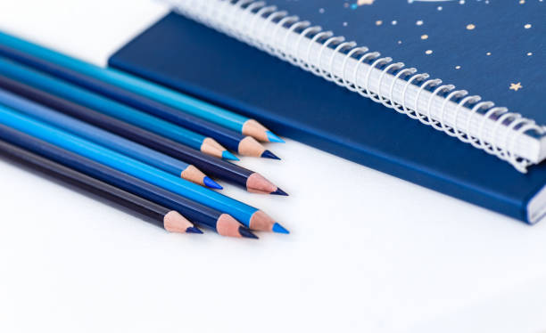 Back to school blue items on white background. Notebook and set of blue pencils. stock photo
