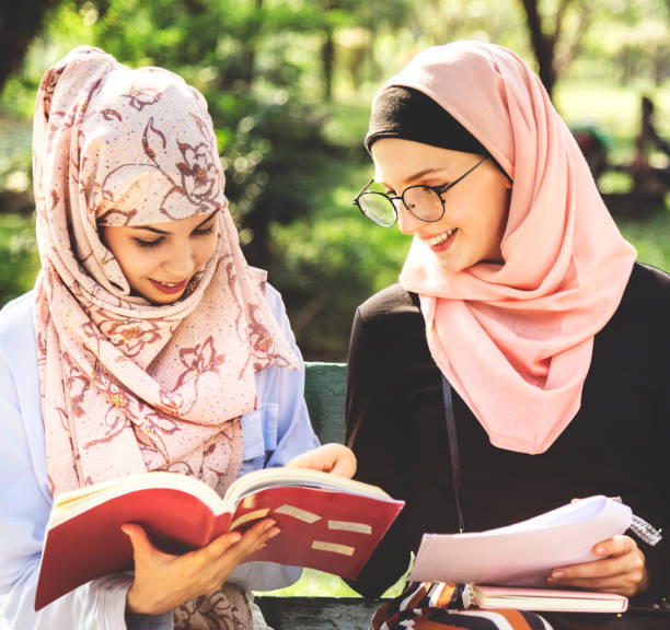istock Friends reading book together at park 1030358312