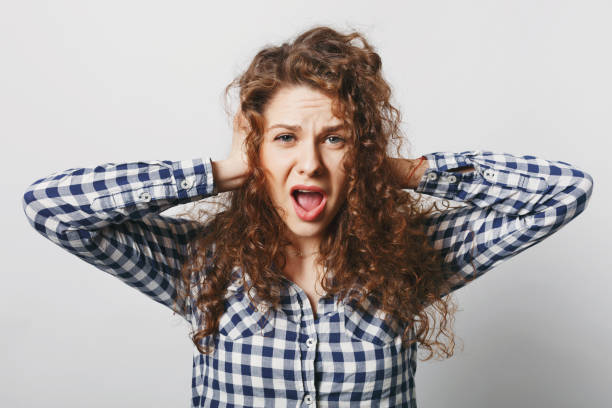 istock Negative emotions and people. Desperate female keeps hands on ears, ignores someone, opens mouth widely, screams with hopelesness, feels anxiety and frustration, isolated over white background 1030358790