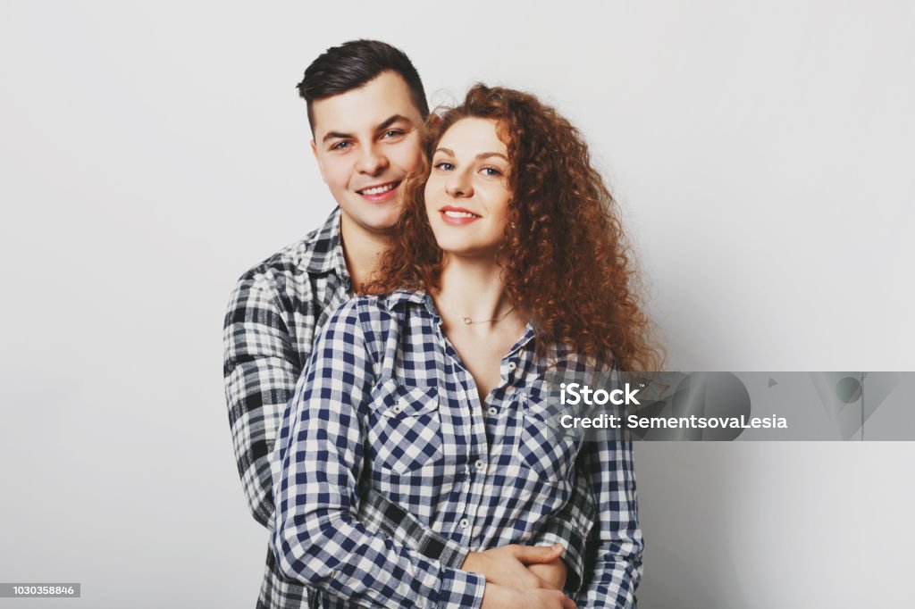 Indoor shot of girlfriend and boyfreind embrace passionately, have happy expressions, demonstrate good feelings, isolated over white background. Lovely curly woman rests with her lover indoor Adult Stock Photo