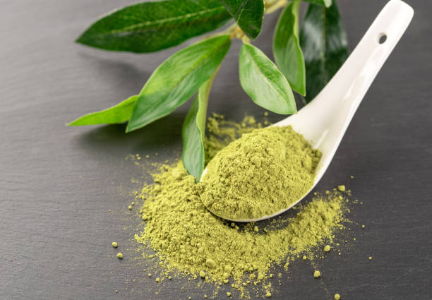istock Matcha powder in White ceramic spoon and tea leaves on black background 1030362262