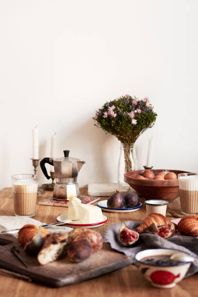 istock Breakfast in modern kitchen with croissants, figs, coffee, bread on board over rustic wooden table background, empty space on white wall 1030367098