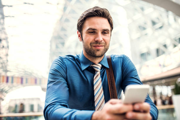 istock A young businessman with smartphone standing in a modern building, texting. 1030371230