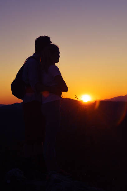 istock Young couple watching glorious sunset over mountains 1030371936
