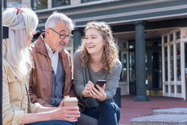 joven muestra abuelo nuevo teléfono inteligente - coat grandfather grandchild granddaughter fotografías e imágenes de stock