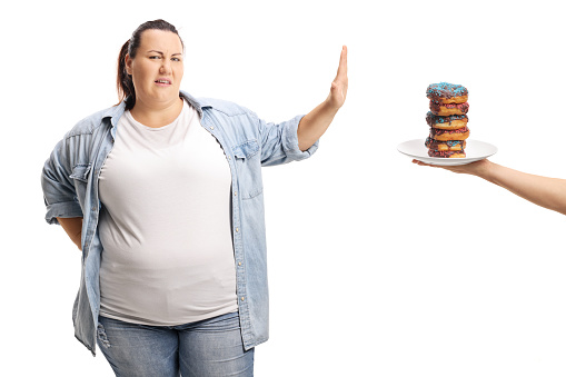 Overweight woman refusing to eat sweets isolated on white background