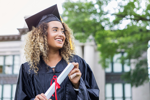 Graduation, education and hug with woman student friends hugging on university campus in celebration of success or qualification. College, graduate and scholarship with a female and friend embracing