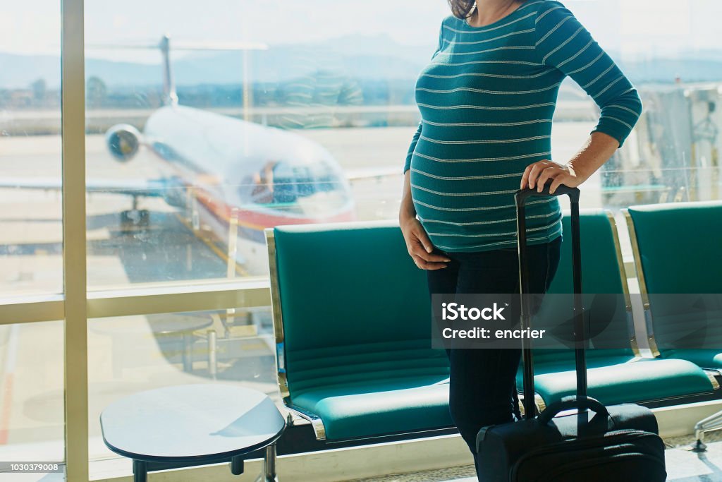Pregnant woman traveling by plane Pregnant woman at second trimester traveling by plane. Mother to be going to vacation or business trip. Is it safe to travel during pregnancy concept Pregnant Stock Photo