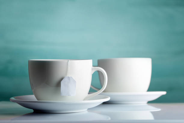 istock Two white porcelain teacups on white table show clean and simple design ideas, selective focus 1030379756