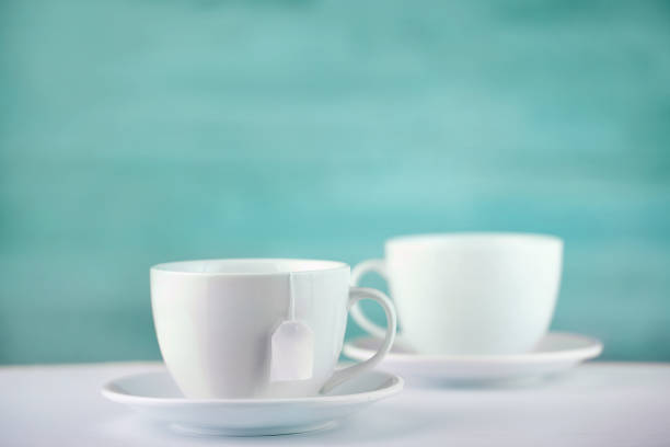 istock Two white porcelain teacups on white table show clean and simple design ideas, selective focus 1030379910