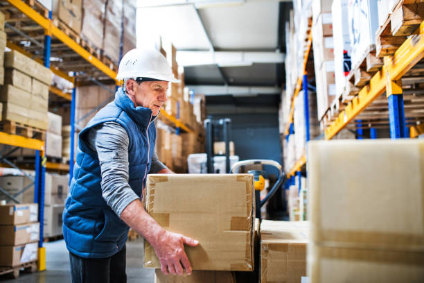 istock Senior male warehouse worker unloading boxes from a pallet truck. 1030380200
