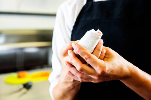 un chef mujer accidentalmente corta su dedo en un comercial de la cocina preparando alimentos. - cortar en trozos preparar comida fotos fotografías e imágenes de stock