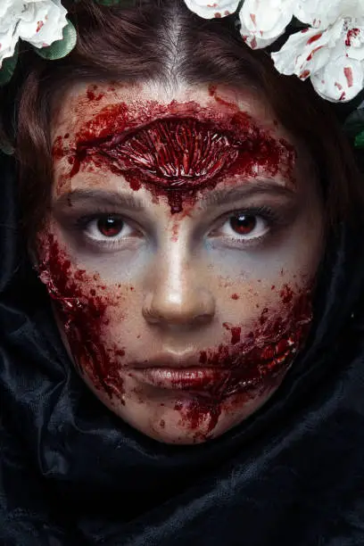 Photo of Portrait of bloody horrible scary zombie girl in a Halloween festive makeup. Red eyes.