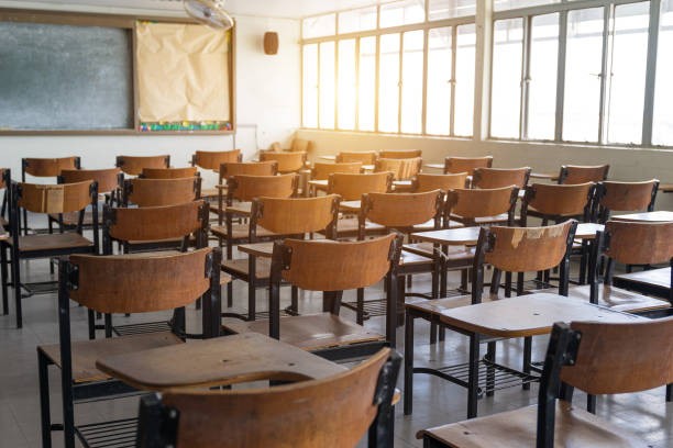 istock Empty classroom with a lot of wooden chairs 1030391248
