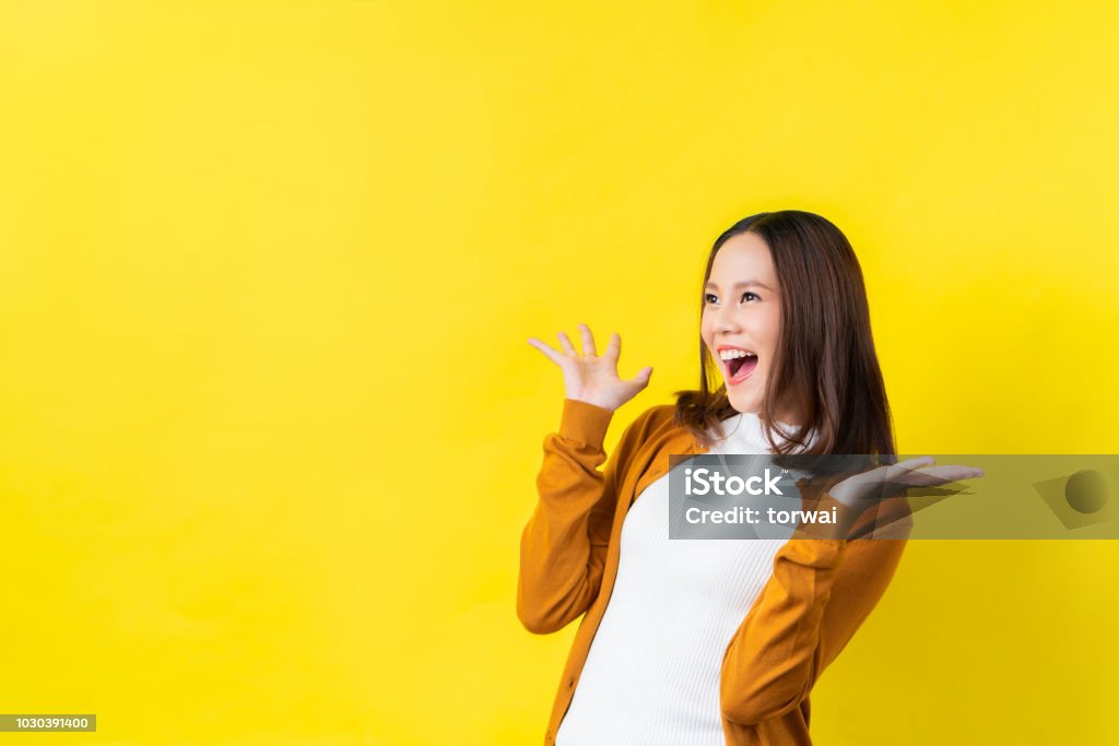 Asian girl is surprised she is excited.Yellow background studio Asian and Indian Ethnicities Stock Photo