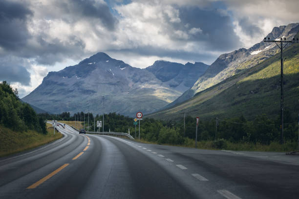 istock Car on road in Norway, clouds over mountains 1030394068