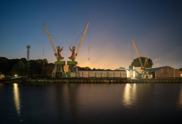 Liepaja port on summer night. Cranes and containers can be seen next to storage hangars.