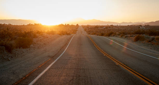 istock Country Road Through Desert Looking Towards Setting Sun On Horizon 1030407866