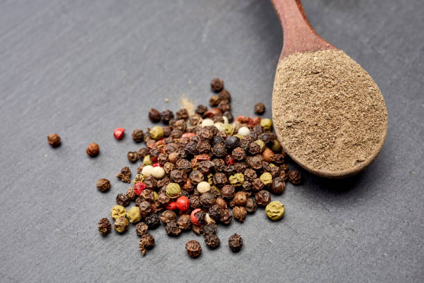 istock Top view on composition of peppercorns in wooden spoon on dark background, close-up. 1030412708