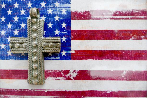 istock Silver colored crucifix lying on a american flag 1030413716