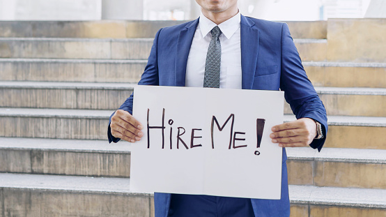 business man holding  board with text hire me on business district , business concept