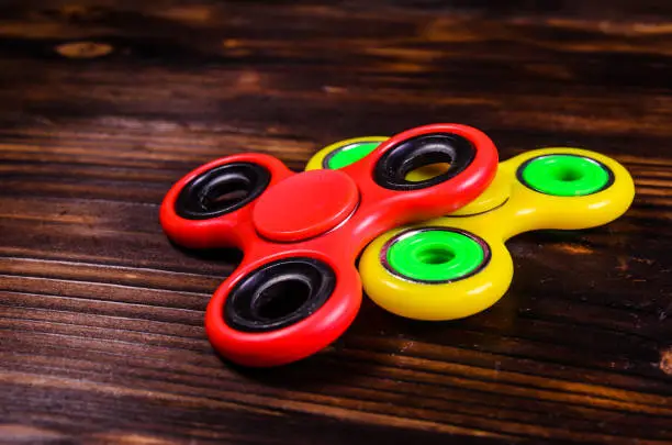 Photo of Two fidget spinners on wooden desk