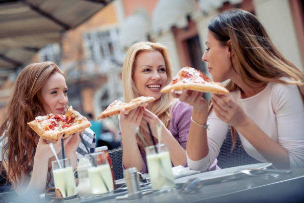 istock Female friends eating pizza in cafe 1030434986