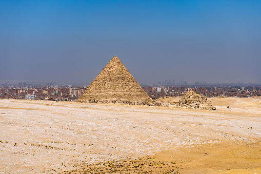 The Pyramids of Giza, man-made structures from Ancient Egypt in the golden sands of the desert with polluted Cairo in the background