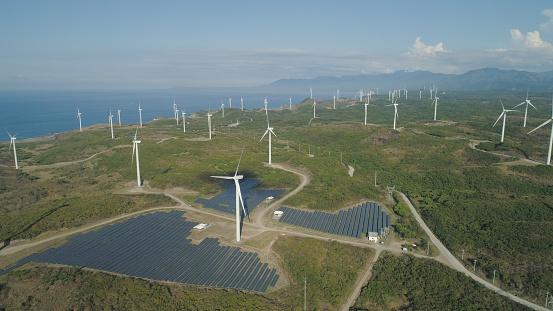 Aerial view of Windmills for electric power production on the seashore. Bangui Windmills in Ilocos Norte, Philippines. Solar farm, Solar power station. Ecological landscape: Windmills, sea, mountains. Pagudpud.