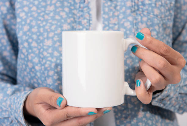 istock Hand holding white ceramic coffee cup. mockup for creative design branding. 1030452088
