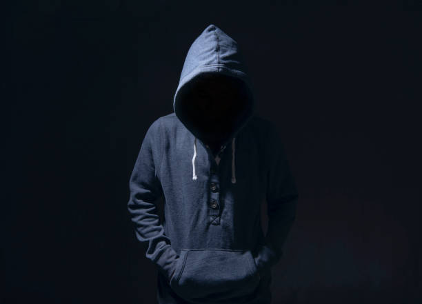 istock Mysterious man with hoodie in silhouette on black background. committed a crime concept. 1030452126