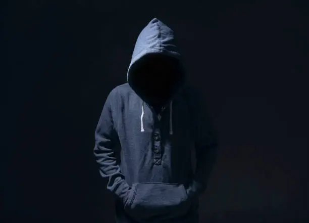 Mysterious man with hoodie in silhouette on black background. committed a crime concept.