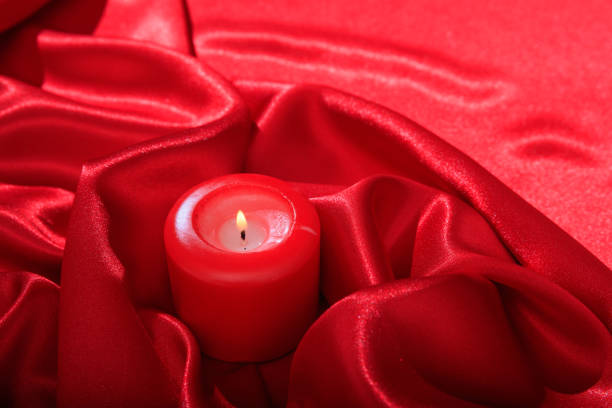Candle on red satin background