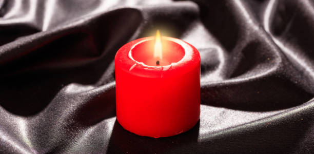 istock Red candle on black satin background 1030458290