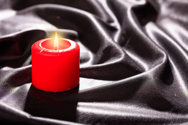 istock Red candle on black satin background 1030458292
