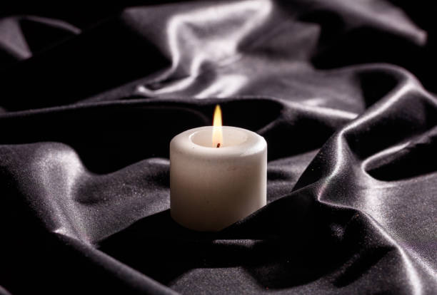 istock White candle on black satin background 1030458298