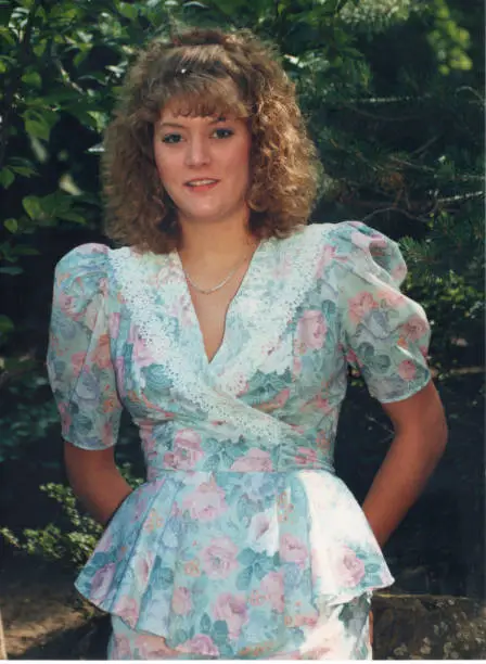 Outdoor picture of a blond teen girl wearing a pink and blue dress in the summer