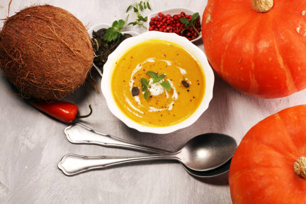 Roasted pumpkin and carrot soup with cream and pumpkin seeds on stone background.