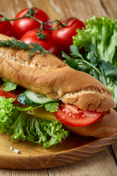 istock Fresh sandwich with lettuce, tomatoes and cheese served on wooden plate over rustic background, selective focus 1030467720