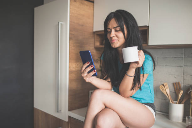 istock Young woman reads her messages while drinking coffee 1030467814